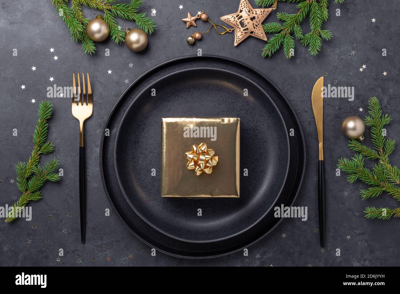 Table de Noël. Assiette en céramique noire avec boîte cadeau dorée, branche  en sapin et accessoires sur fond de pierre. Décoration or - image Photo  Stock - Alamy