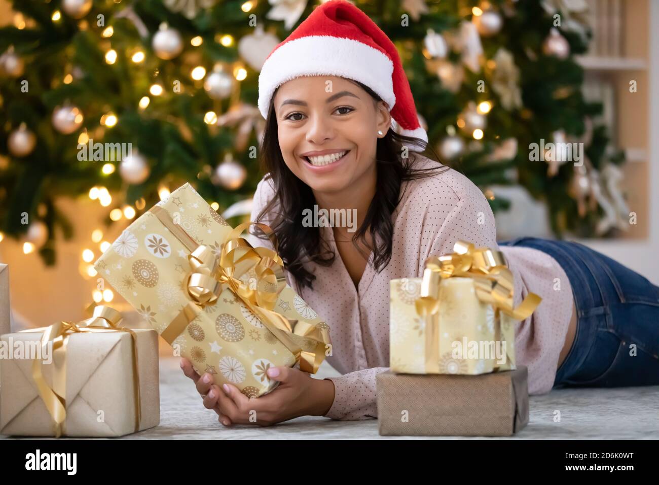 Portrait d'une femme biraciale souriante en chapeau de père Noël rouge Banque D'Images