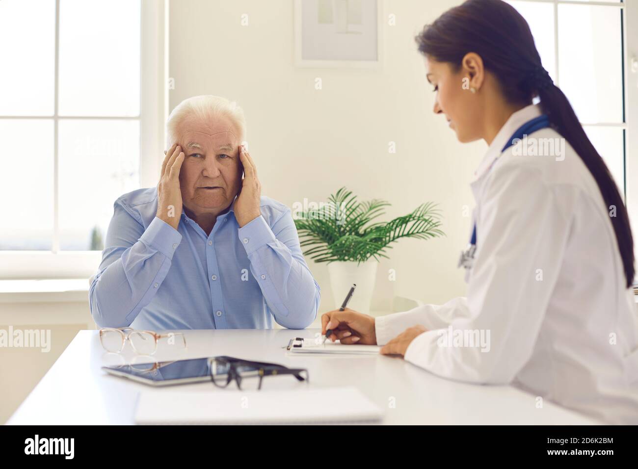 Homme âgé se plaignant de maux de tête, de stress ou de troubles de la vue pendant une entrevue médicale Banque D'Images