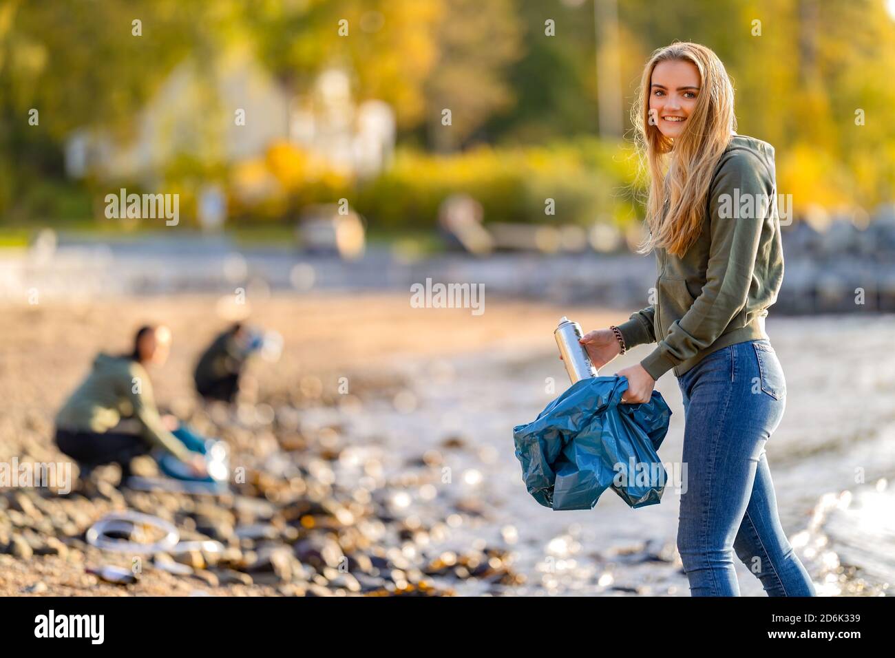 Jeunes volontaires dédiés au nettoyage de la plage le jour ensoleillé Banque D'Images