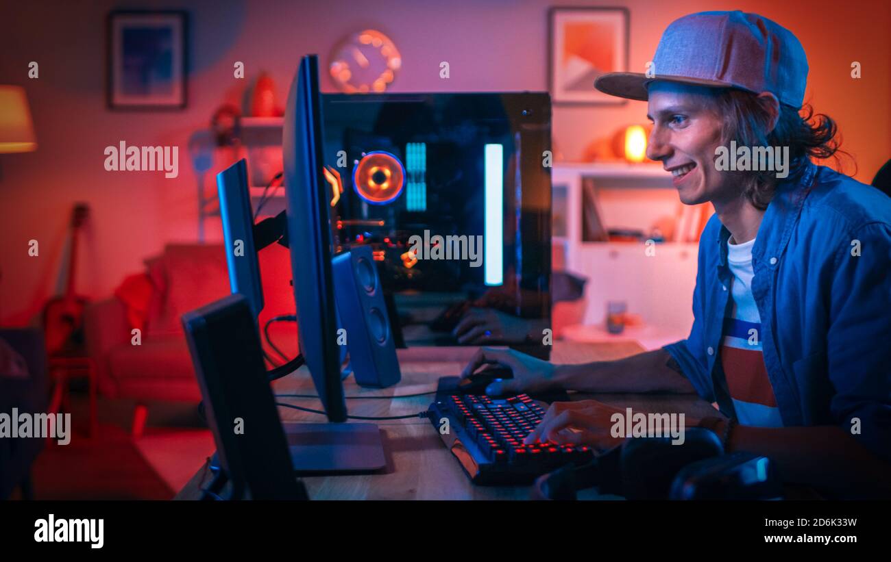 Joueur professionnel jouant jeu vidéo en ligne jeu de tir à la première personne sur son ordinateur personnel puissant avec des lumières LED néon colorées. Le jeune homme est Banque D'Images