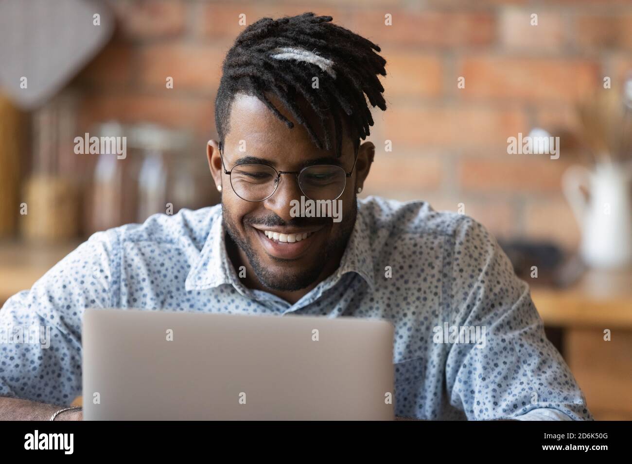 Homme biracial souriant en lunettes travail sur ordinateur portable Banque D'Images