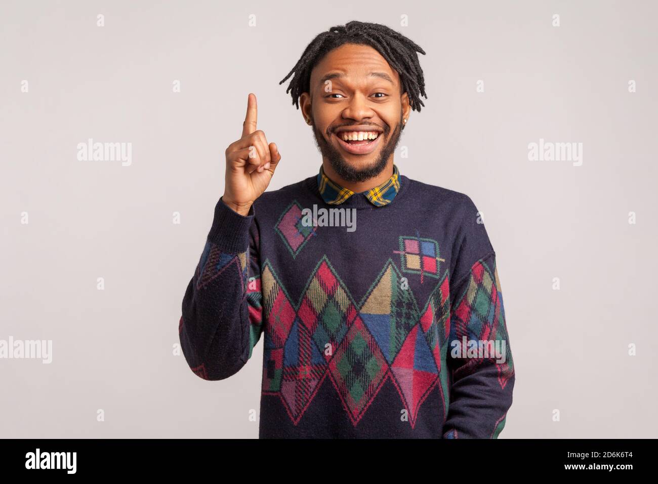 Un homme africain extrêmement heureux avec des dreadlocks dans un sweat-shirt élégant pointant le doigt vers le haut avec le sourire crasseux sur le visage, intelligent homme a l'idée, démarrage. JE Banque D'Images