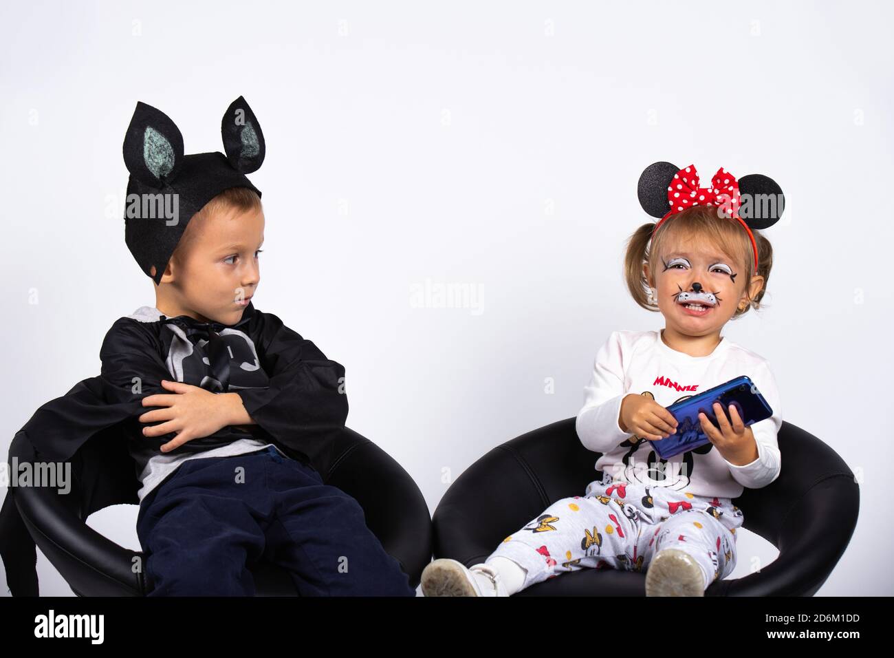 Les enfants attendent Halloween en costumes de fête. Le garçon est offensé, la fille ne partage pas le téléphone. Photo en intérieur sur fond blanc. Banque D'Images