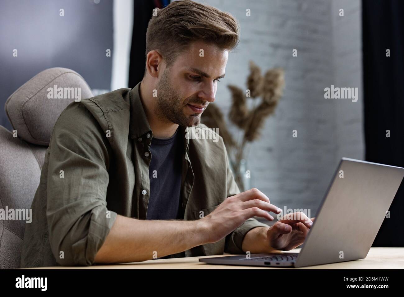 Jeune indépendant travaillant à la maison avec un ordinateur portable. Envoi de SMS, navigation sur Internet. Études en ligne, formation en ligne, travail à distance. Jeunes Banque D'Images