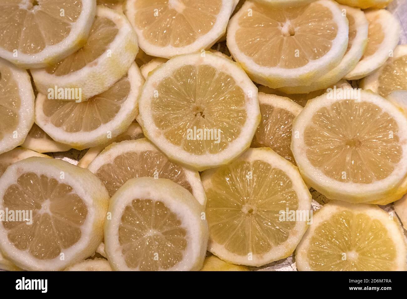 citron entier et citron entier sur un lit de citrons et limes en tranches Banque D'Images