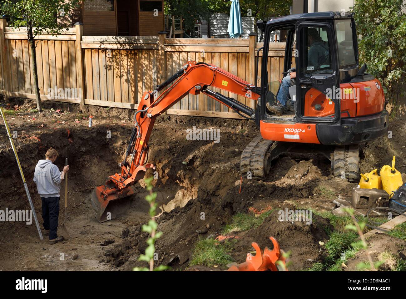 Pelle hydraulique dans la cour arrière creusant la terre hors d'un trou Pour une piscine à Barrie, Ontario Banque D'Images