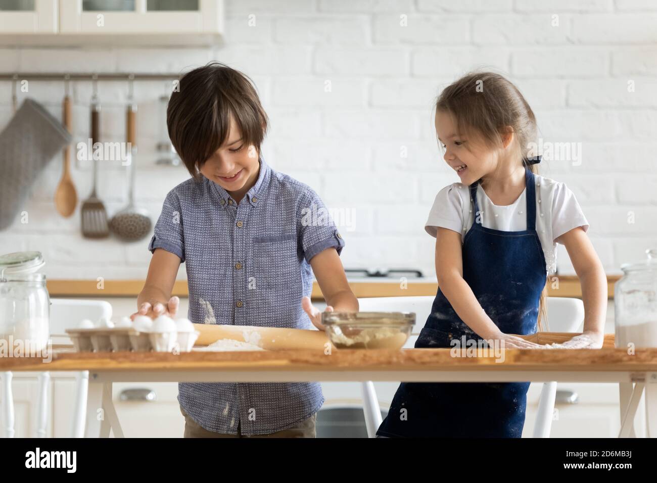 Deux petits enfants heureux cuisant ensemble, en faisant rouler la pâte Banque D'Images