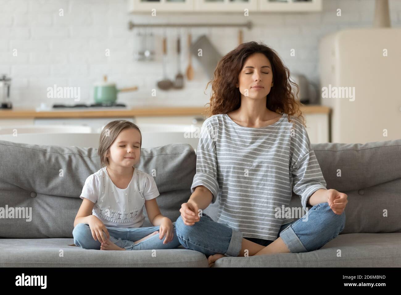 Paisible jeune mère et petite fille méditant, faisant de l'exercice de yoga Banque D'Images