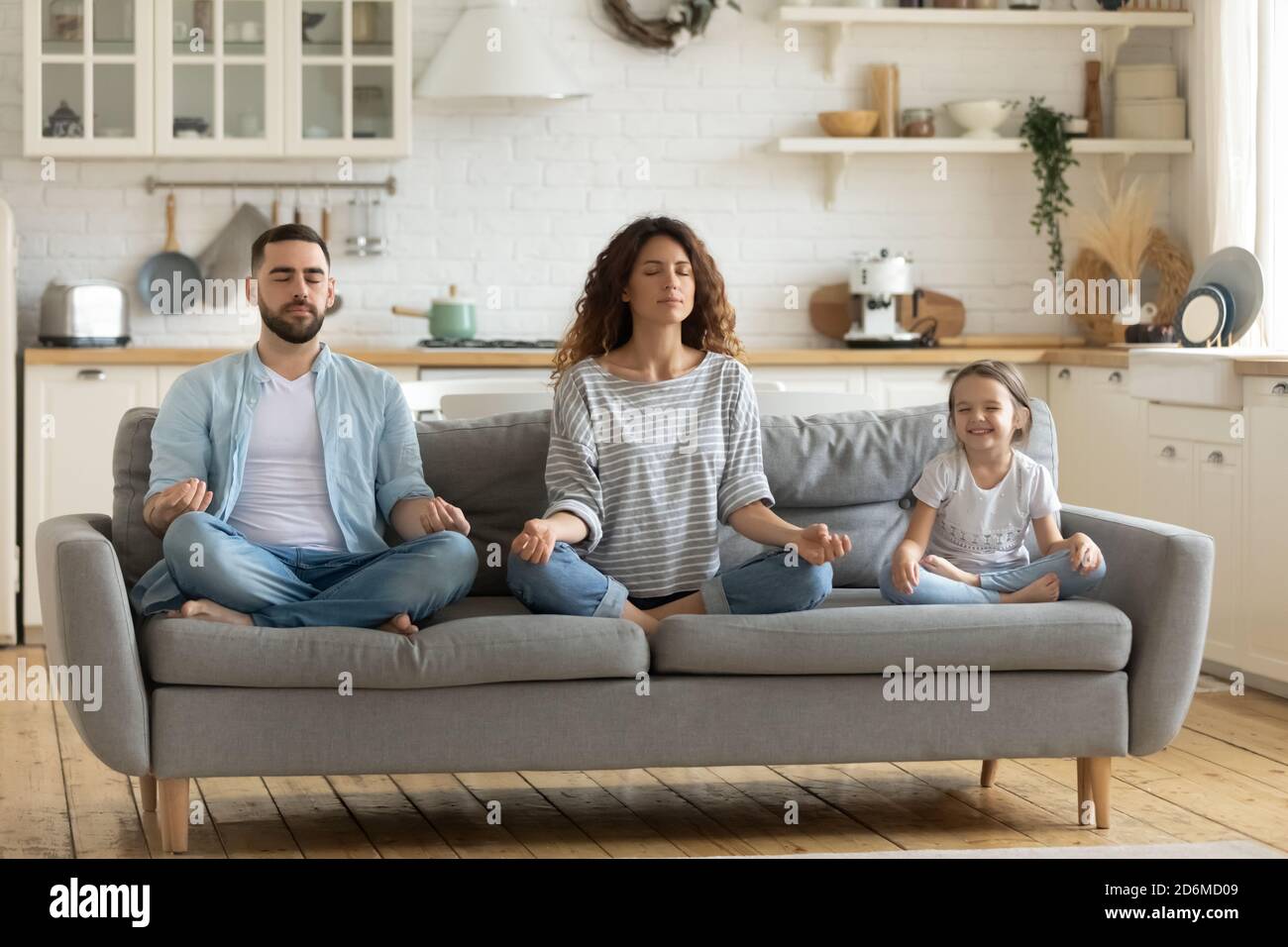 Paisible jeune mère et père avec petite fille pratiquant le yoga Banque D'Images