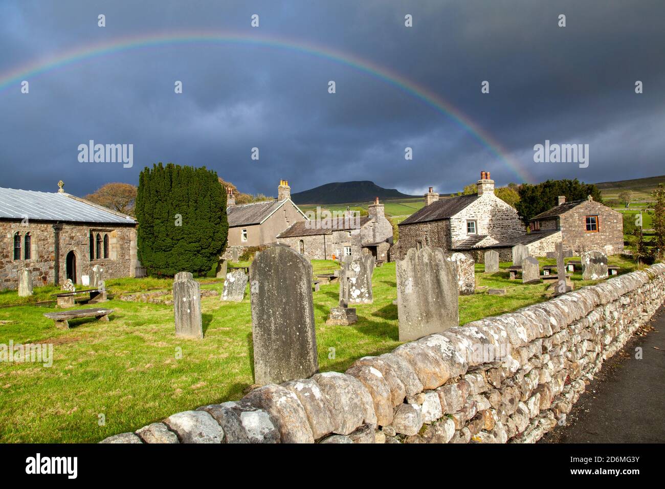 Arc-en-ciel au-dessus de l'église du village de St Oswald dans le Yorkshire village de Horton à Ribblesdale avec la montagne de Pen-y-gand sur la Pennine Way Banque D'Images