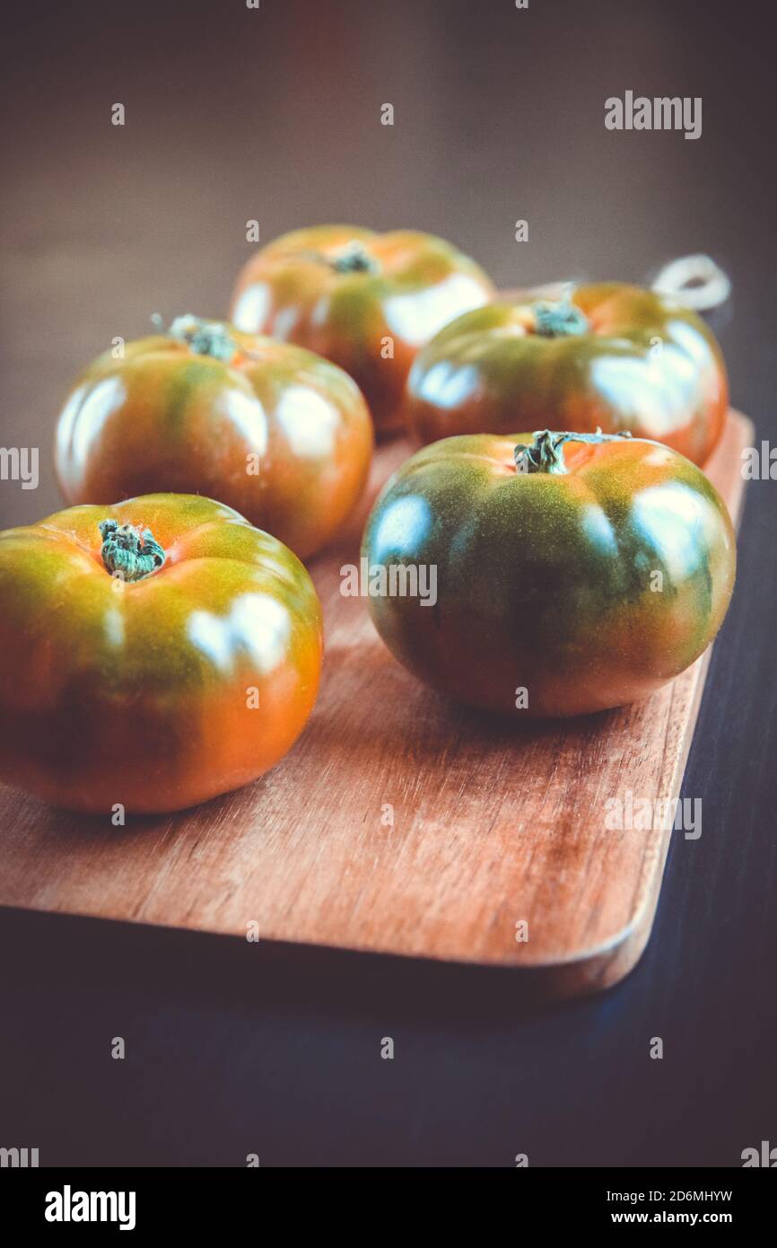 Tomates biologiques en jante noire sur une planche à découper en bois Banque D'Images