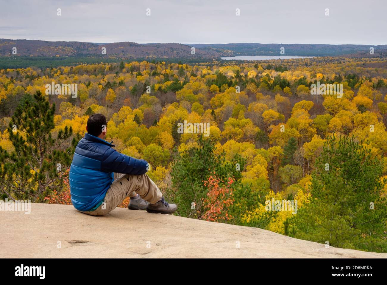 Un homme assis au bord de la falaise, regardant le paysage d'automne canadien Banque D'Images