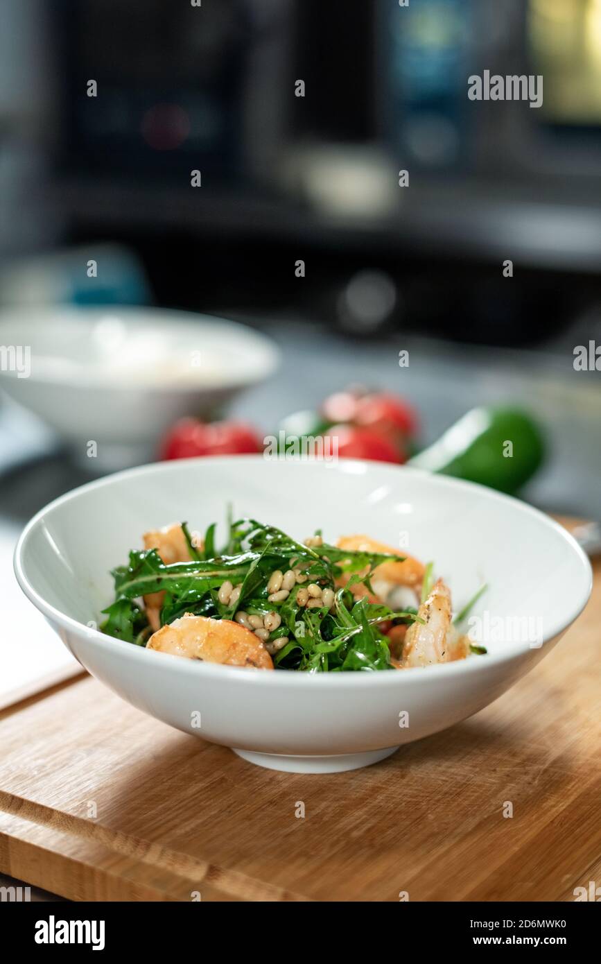 Planche en bois avec bol en céramique blanc contenant de la salade appétissante pour client Banque D'Images