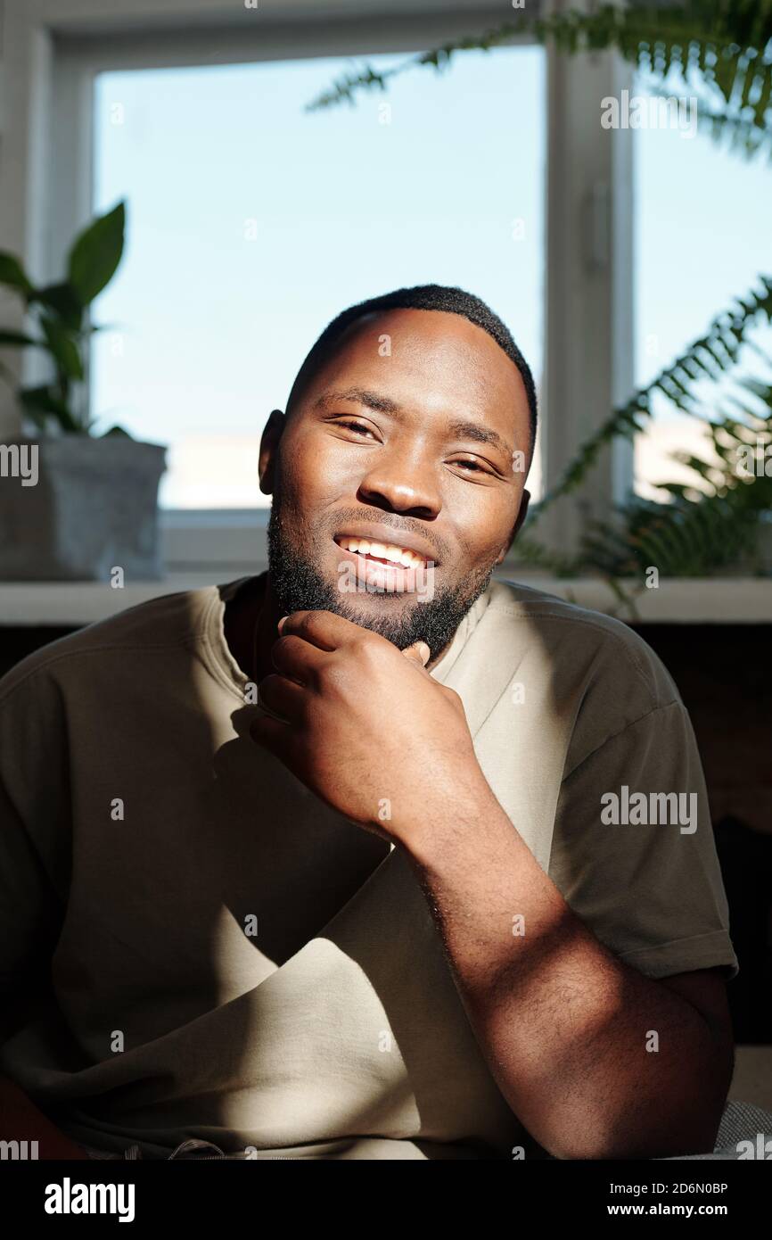 Joyeux jeune homme d'origine africaine qui vous regarde un sourire éclatant Banque D'Images
