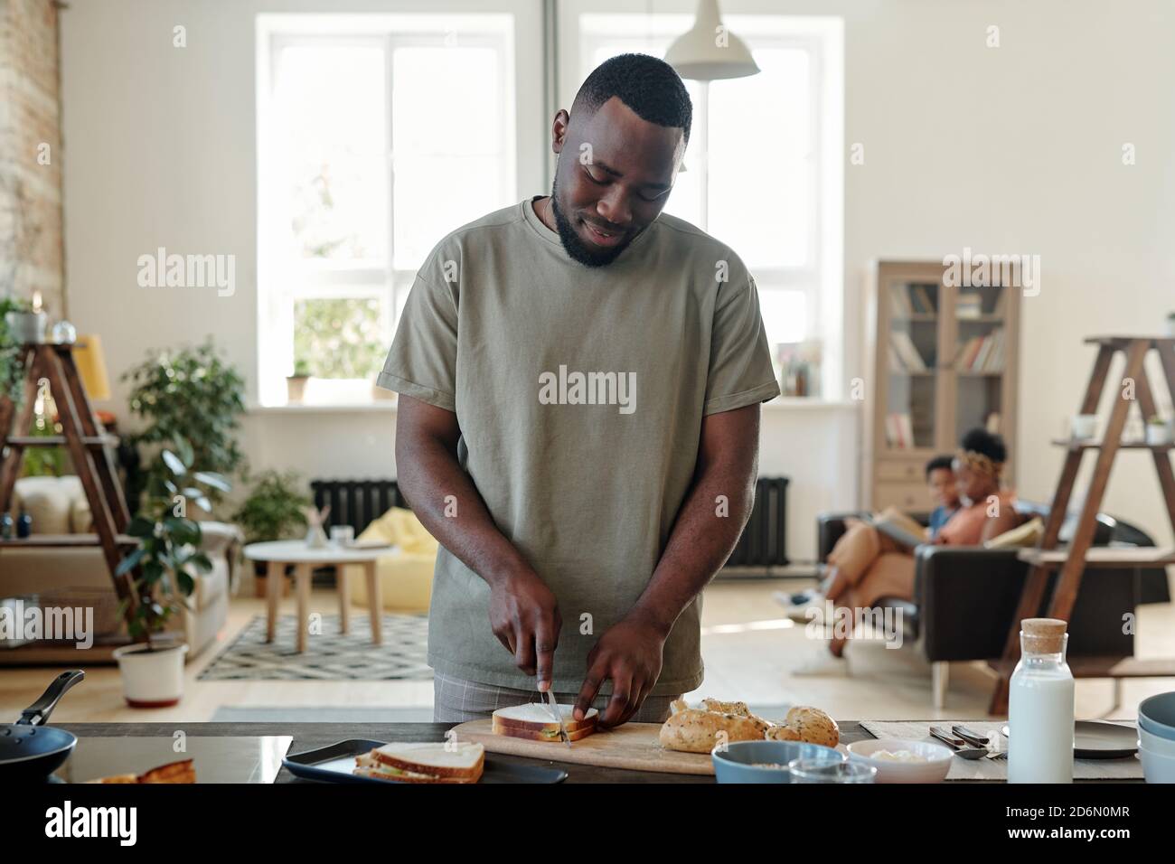 Jeune barbu d'origine africaine préparant des sandwichs pour le petit déjeuner Banque D'Images
