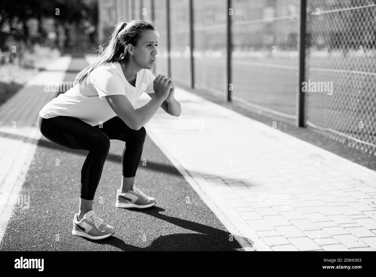 Femme motivée qui fait des squats profonds à l'air frais Banque D'Images