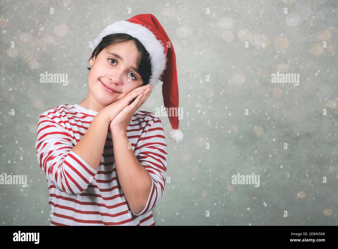 Joyeux Noël, jeune fille souriante portant le chapeau de Noël du Père Noël pendant noël arrière-plan Banque D'Images