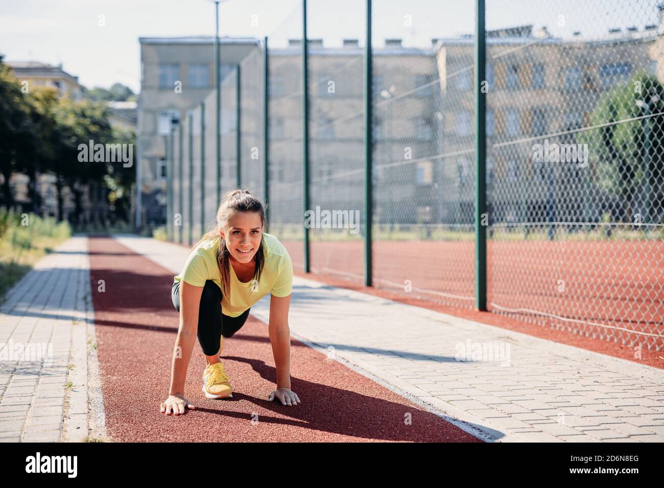 Une jeune athlète féminine commence à courir sur la piste rouge Banque D'Images