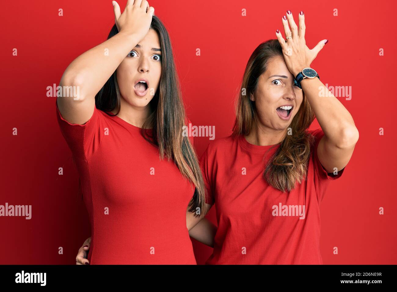 Famille hispanique de la mère et de la fille portant des vêtements décontractés sur fond rouge surpris avec la main sur la tête pour l'erreur, souvenez-vous de l'erreur. oublié, mauvais Banque D'Images Famille hispanique de la mère et de la fille portant des vêtements décontractés sur fond rouge surpris avec la main sur la tête pour l'erreur, souvenez-vous de l'erreur. oublié, mauvais Banque D'Images