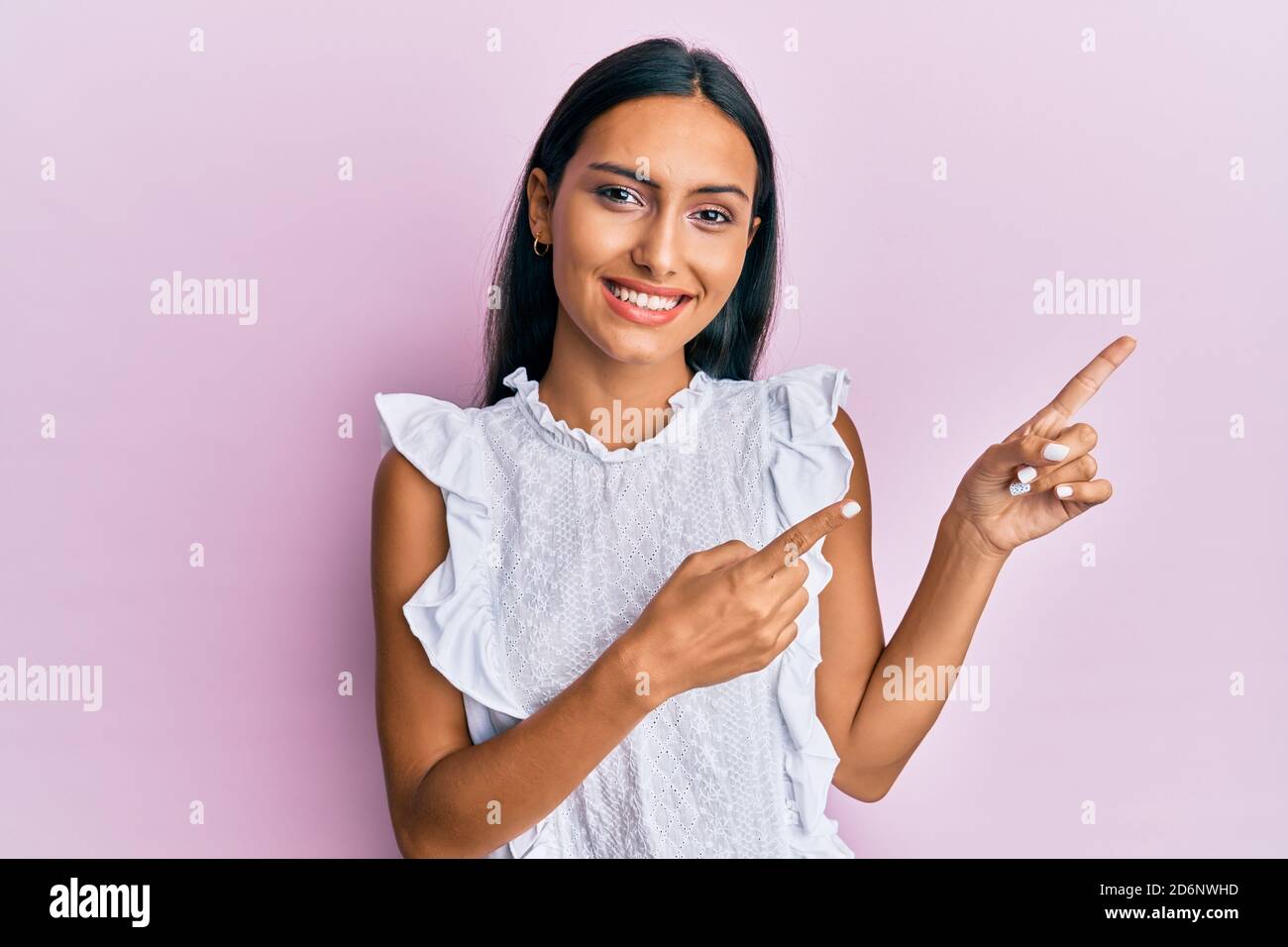 Jeune femme brune portant une chemise d'été élégante souriant et regardant la caméra pointant avec deux mains et des doigts sur le côté. Banque D'Images