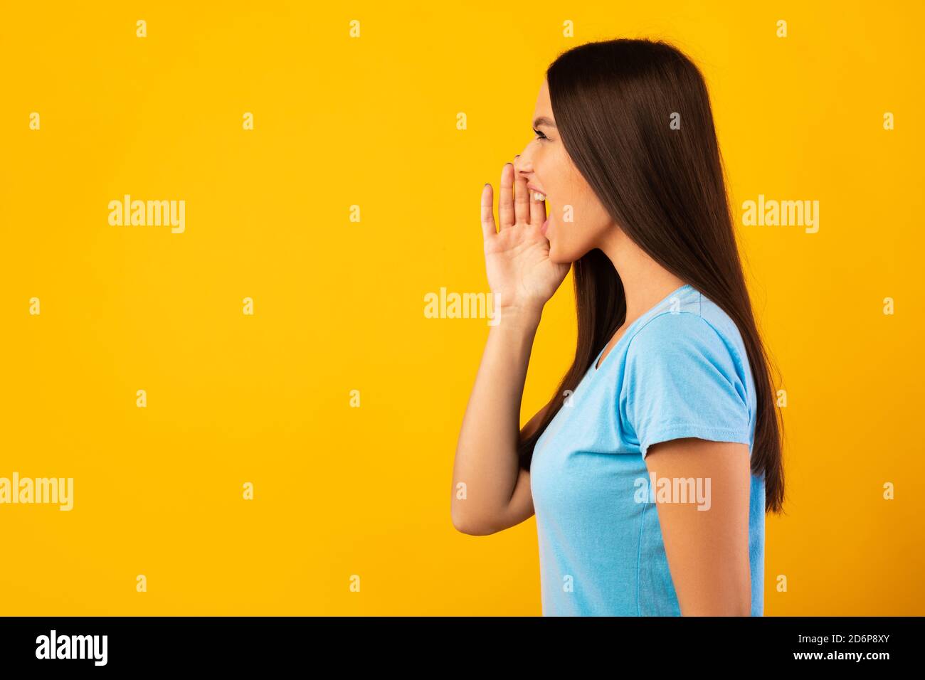 Dame tenant la paume près de la bouche, criant de côté à l'espace d'imitation Banque D'Images