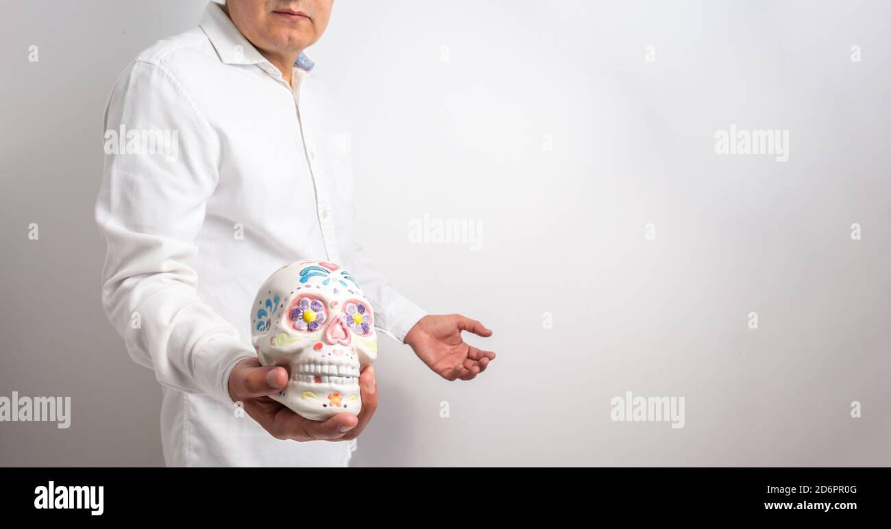 L'homme isolé sur fond blanc montre un crâne peint le jour des morts ou de l'halloween. Mise au point sélective Banque D'Images