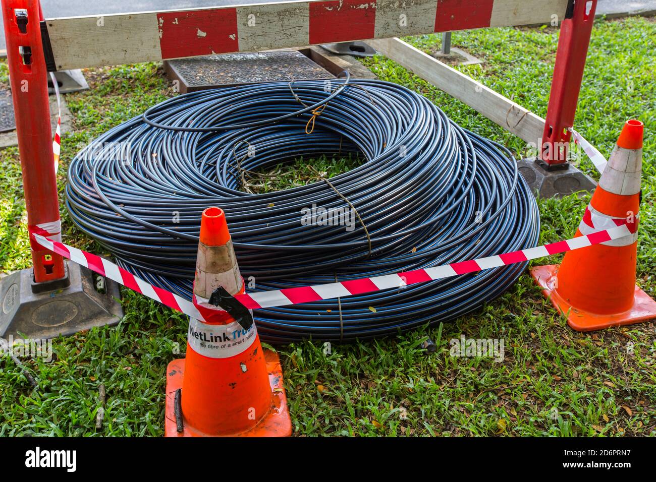 Les câbles à fibre optique industrielle sont enroulés et placés sur l'herbe, les cônes sont autour pour indiquer de ne pas les enlever. Banque D'Images
