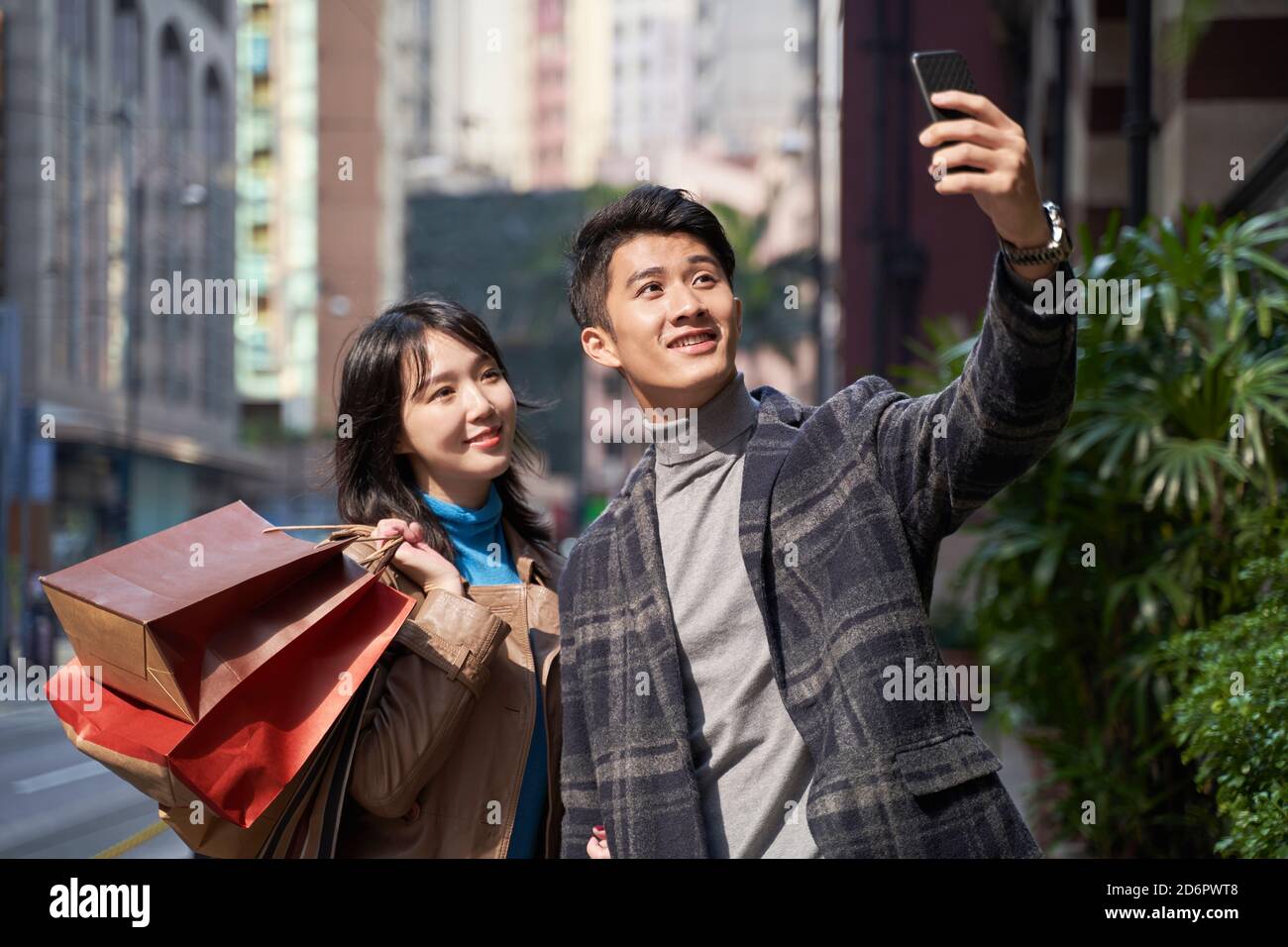 un jeune couple asiatique heureux et aimant prend un selfie pendant marche et shopping dans une ville moderne Banque D'Images
