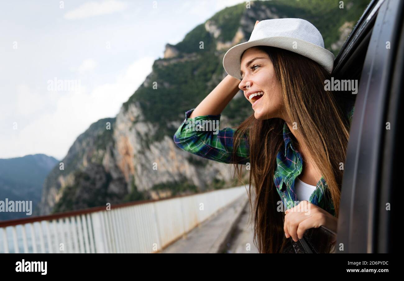 Une femme en voiture en voyage sur route en signe de sourire à la fenêtre Banque D'Images