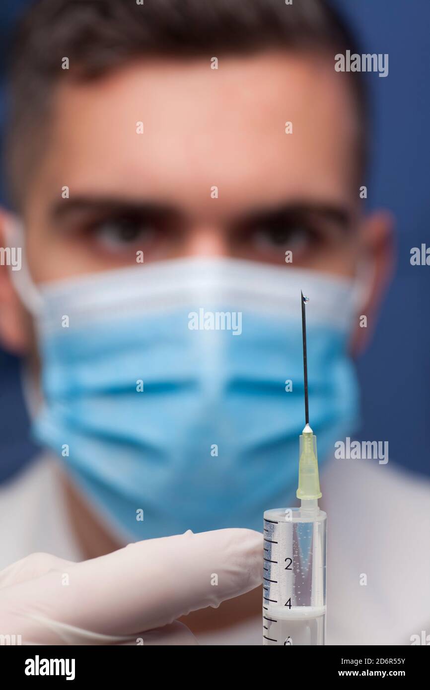 Gros plan du médecin avec un masque médical préparant une seringue pour vaccination - concentrez-vous sur l'aiguille Banque D'Images