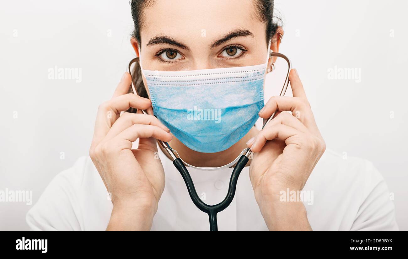 Portrait d'un médecin expérimenté portant un masque de protection et un stéthoscope à ses oreilles lorsqu'il travaille à l'hôpital. Pandémie, covid, virus protecti Banque D'Images