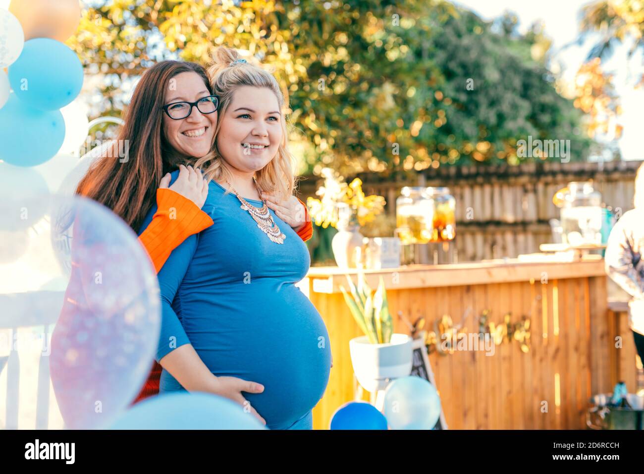 Femme enceinte avec une amie qui l'embrasse sur une installation de fête de douche de bébé. Banque D'Images