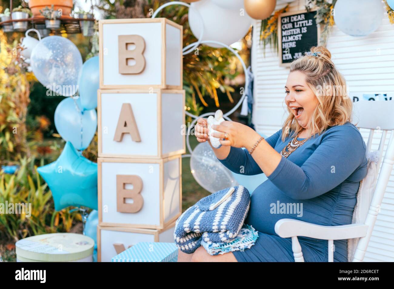 La femme enceinte s'assoit sur une fête de douche de bébé et regarde les cadeaux, souriant heureux, et excitant Banque D'Images
