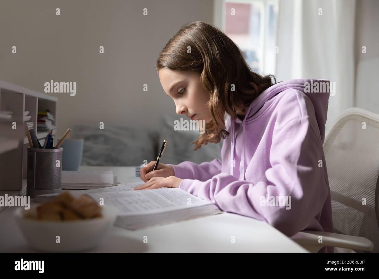 Smart Teen Girl étudier avec un manuel à la maison Banque D'Images