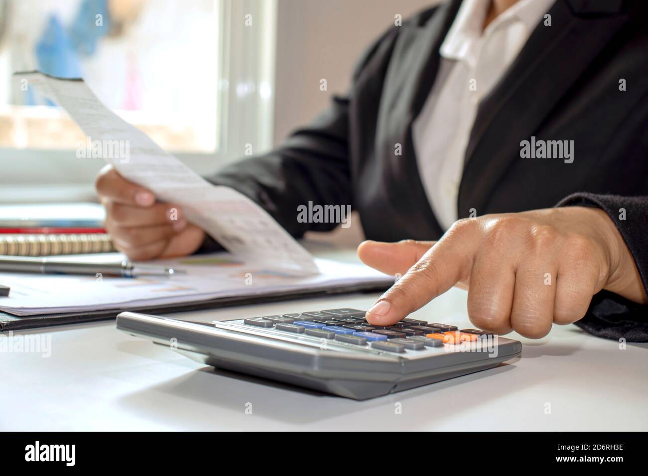 Les femmes d'affaires portent des combinaisons noires avec des calculatrices à doigt pour calculer les dépenses de bureau. Idées d'économie d'argent. Banque D'Images