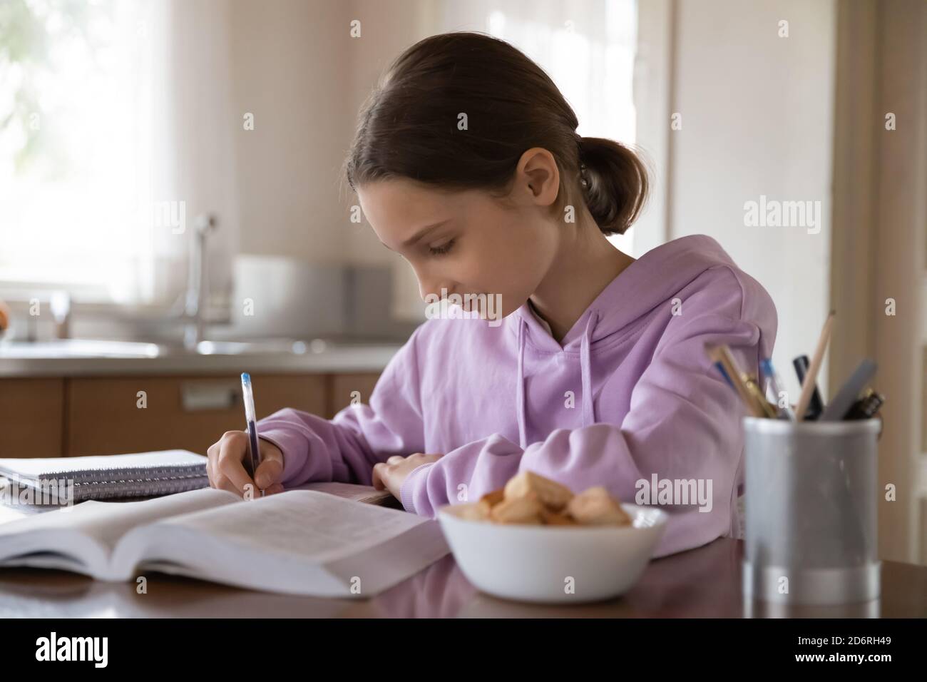 Une jeune fille intelligente prépare ses devoirs à la maison Banque D'Images