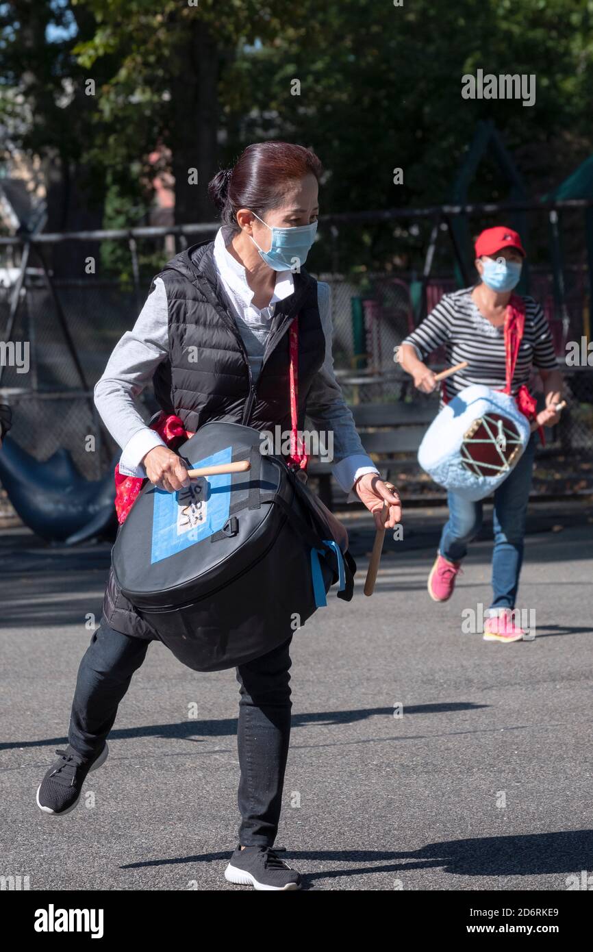Les membres asiatiques américains d'un ensemble de tambours répètent dans un parc à Queens, New York, tout en portant un masque chirurgical. Banque D'Images