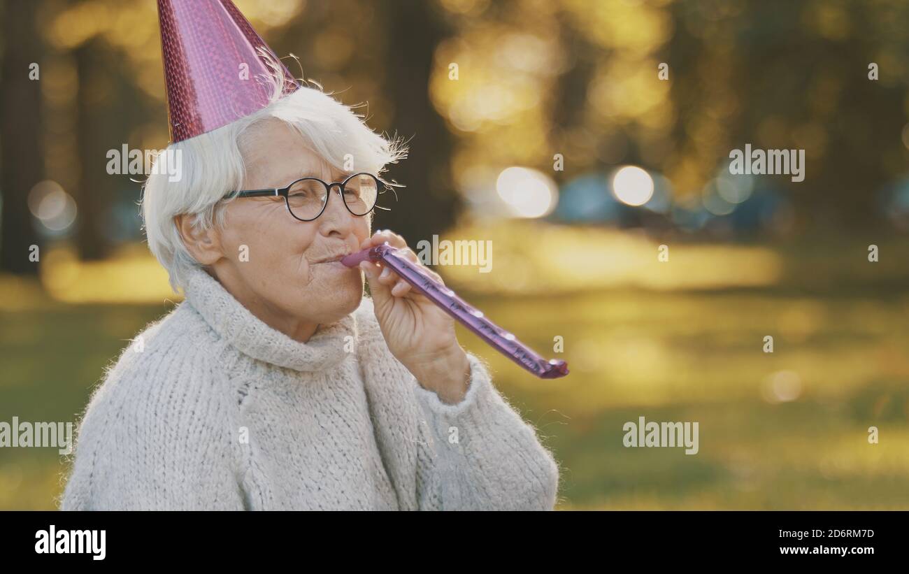 Femme âgée avec chapeau de fête et sifflet enjouant la célébration d'automne dans le parc. Photo de haute qualité Banque D'Images