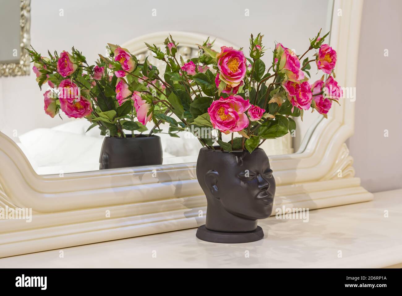 Magnifique intérieur moderne. Fleurs sur la table devant le miroir. Banque D'Images