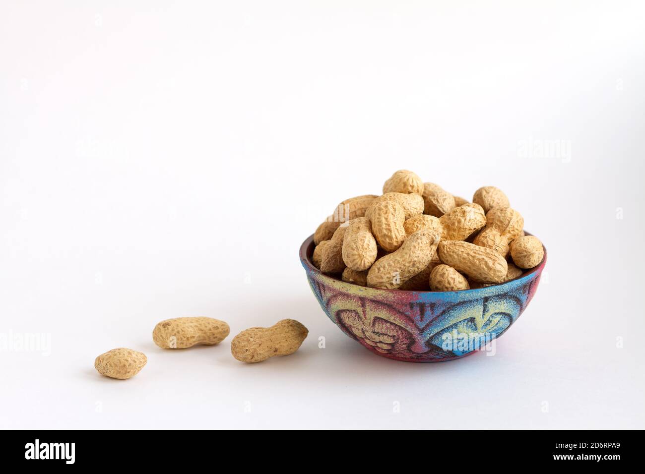 arachides crues en coquille sur une tasse d'argile, arachides sur fond blanc. Copier l'espace pour le texte Banque D'Images