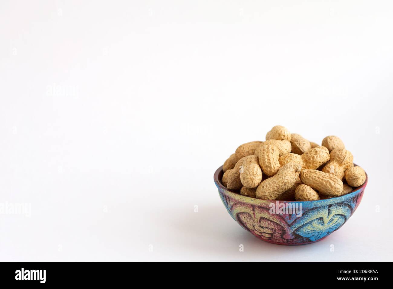 cacahuètes brutes en coquille sur belle tasse sur fond blanc, espace de copie Banque D'Images