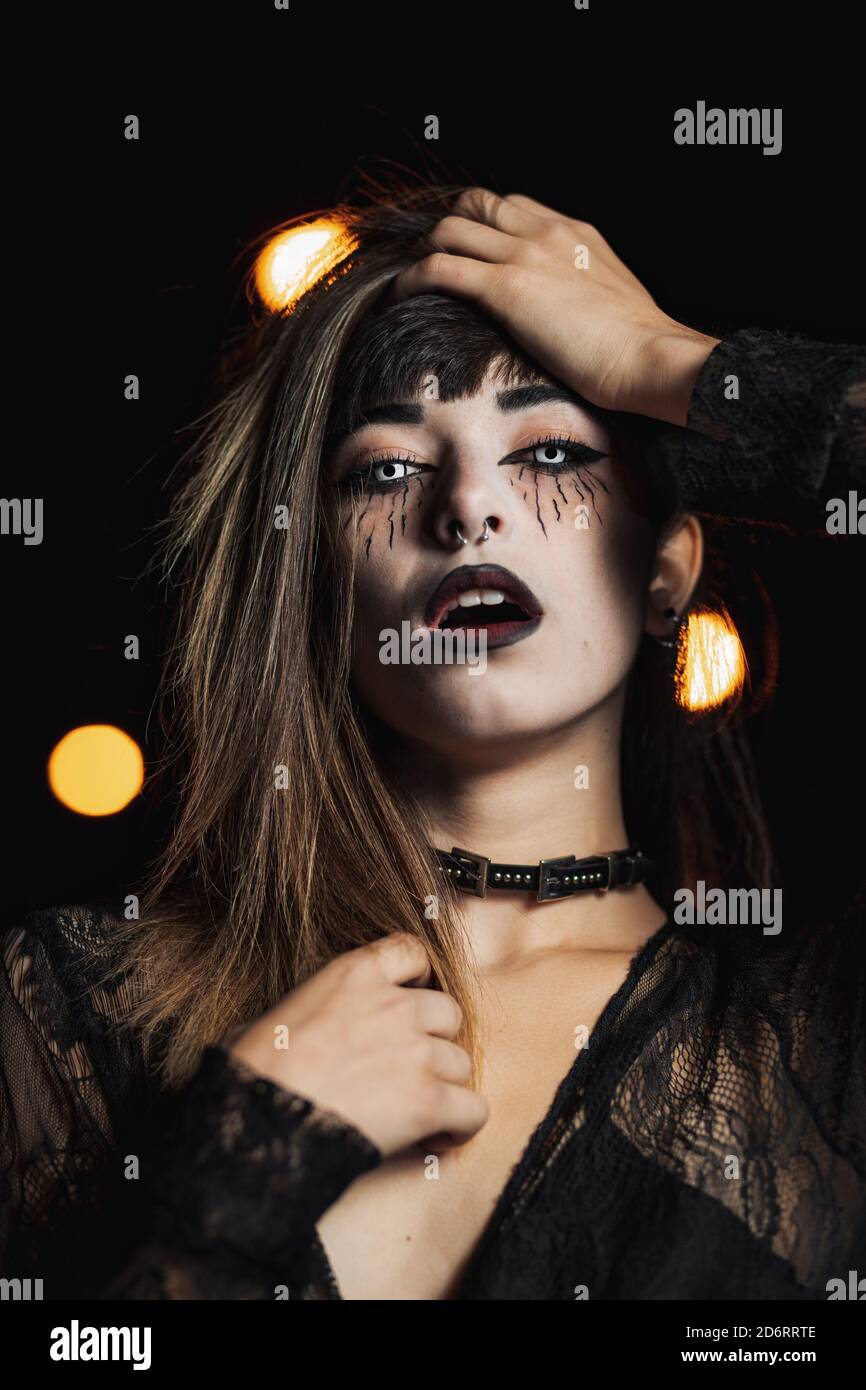 Femme sans émotion en robe noire et avec un maquillage effrayant debout  Dans les lentilles de contact blanches sur Halloween dans l'obscurité tout  en regardant à l'appareil photo Photo Stock - Alamy
