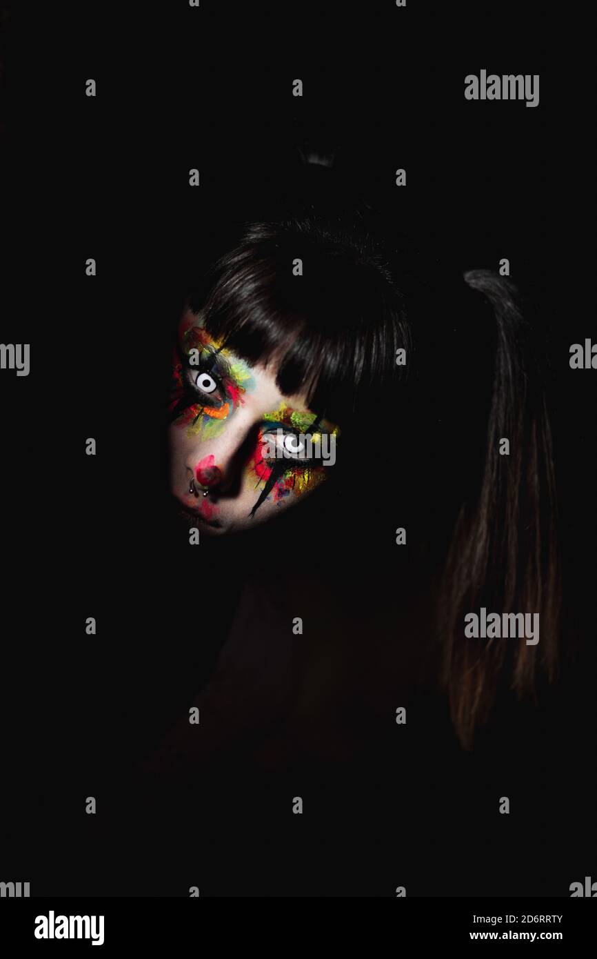 Femelle créepy avec visage peint et dans les lentilles de contact peeping Il n'y a plus de noir la nuit pour Halloween Banque D'Images