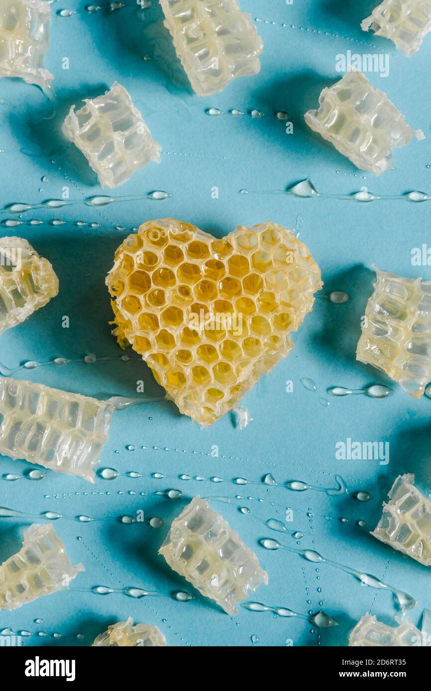 De dessus de coeur brillant en forme de nid d'abeille avec le miel délicieux sur fond bleu Banque D'Images