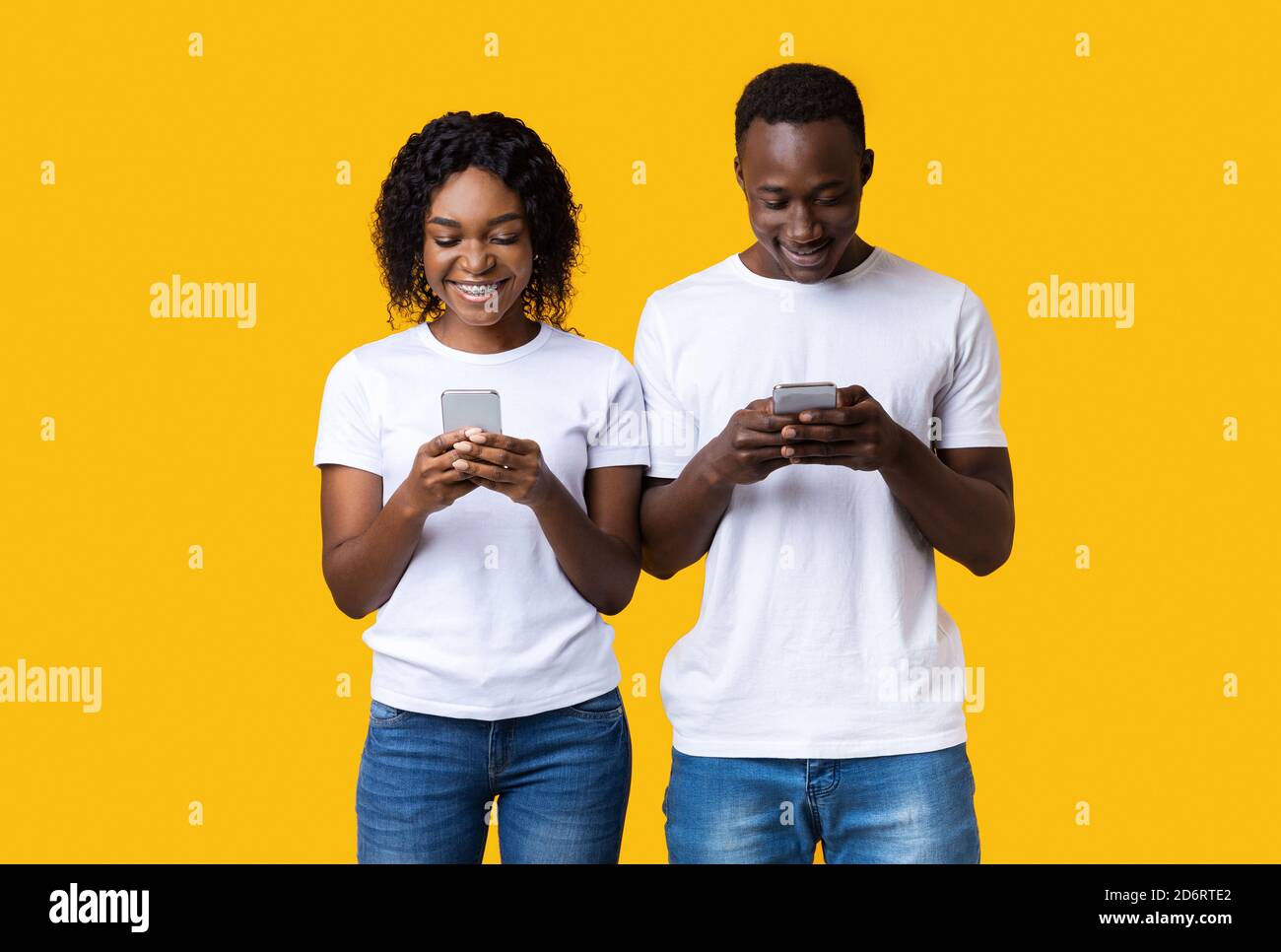 Heureux jeune homme et femme jouer ensemble sur les smartphones Banque D'Images