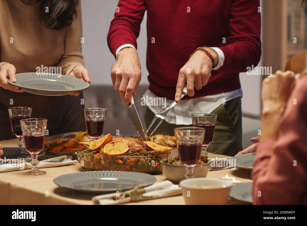 Portrait court d'un homme méconnaissable coupant une délicieuse dinde rôtie tout en dégustant un dîner de Thanksgiving avec des amis et de la famille, espace de copie Banque D'Images