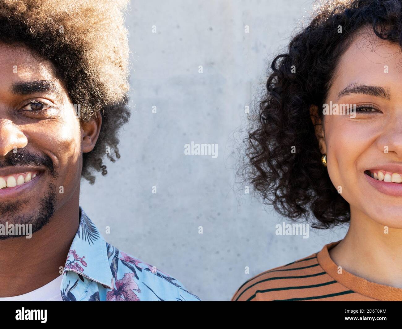Demi-visage de jeune homme et femme noir joyeux avec une coiffure afro debout dans la rue et regardant la caméra le jour ensoleillé Banque D'Images