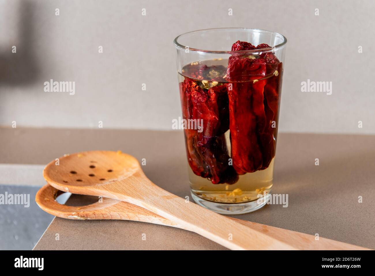 Composition de poivrons rouges picked entiers dans le verre placé dessus table près des spatules en bois Banque D'Images
