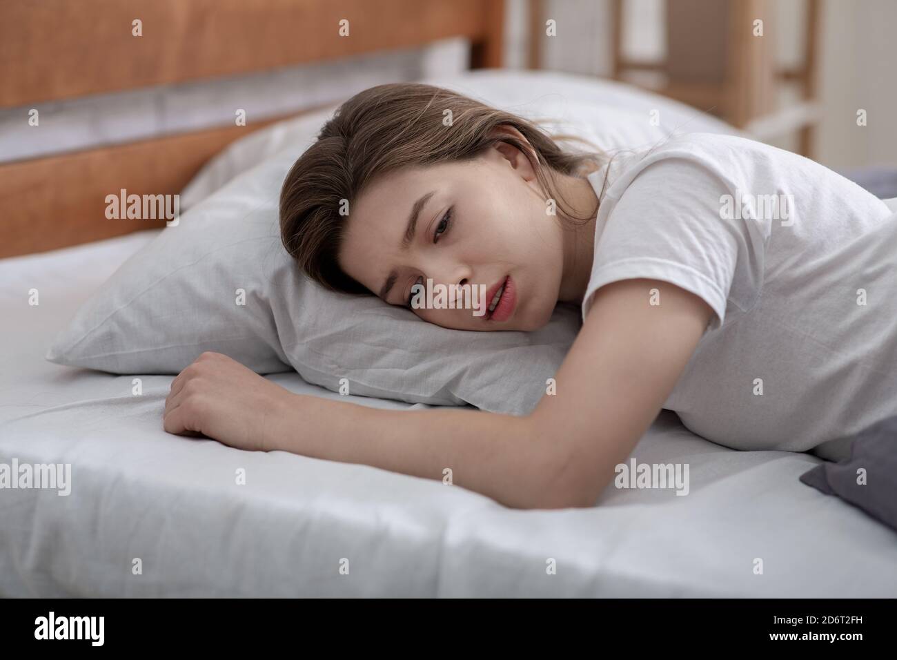 Une jeune femme couché seule dans son lit, pleurant de la perte d'un être cher, souffrant d'une dépression grave Banque D'Images